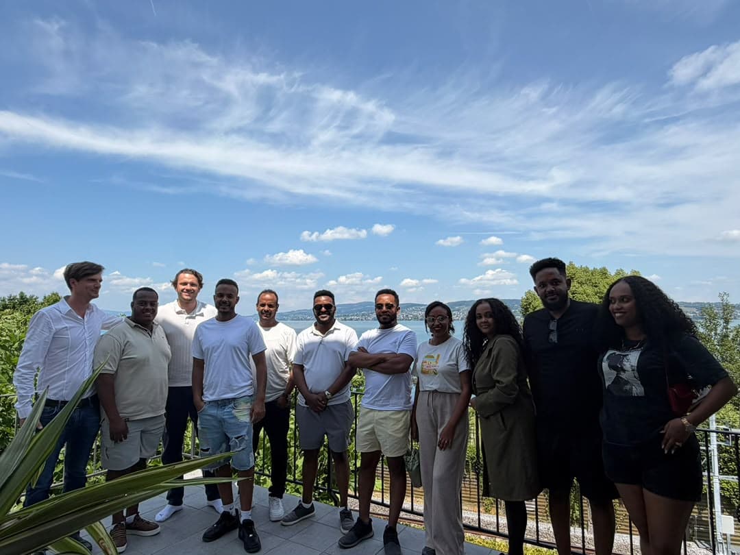 The group standing together on the terrace with the lake and hills in the background